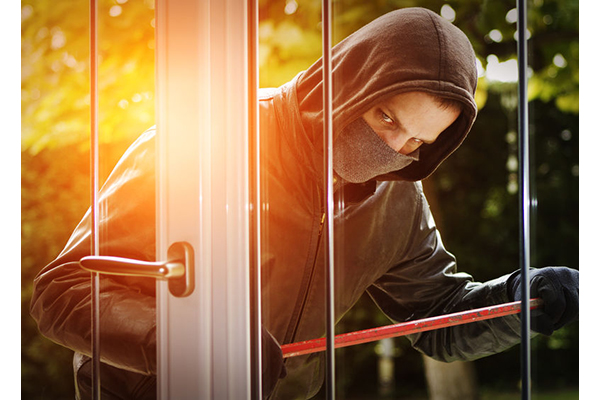 A burglar breaking open a door with a crowbar.