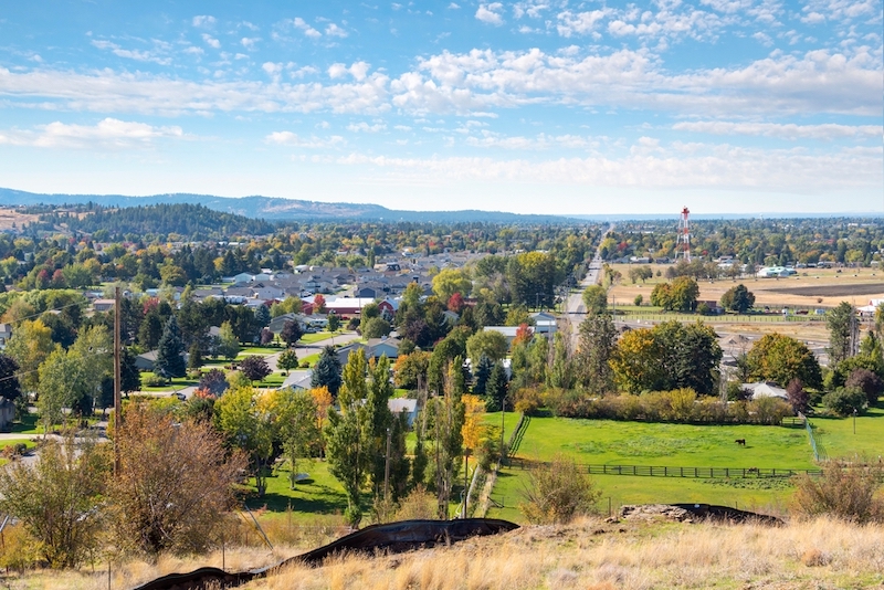 View of Sprague Avenue all the way to downtown Spokane over the cities of Greenacres, Spokane Valley and Veradale, from a hillside in Liberty Lake, Washington, USA at early autumn.